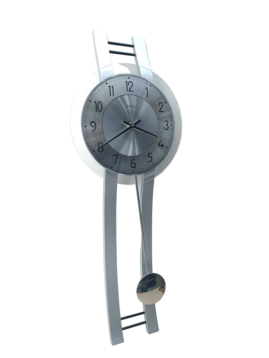 A modern wall clock with a silver metallic circular face and a matching silver pendulum, mounted on a white wall.