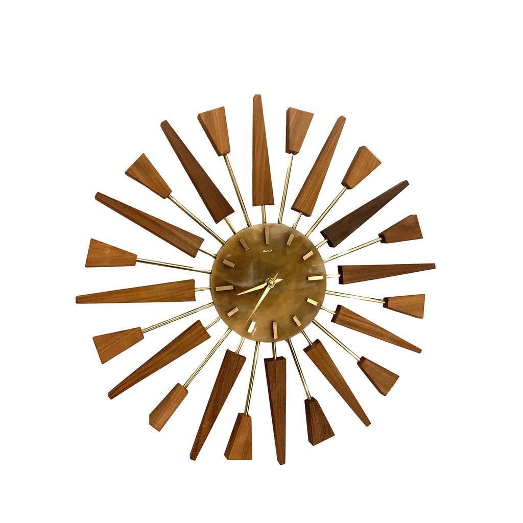 A mid-century modern sunburst wall clock with a circular bronze-toned center, gold-tone hands, and multiple radiating wooden hour markers in varying brown shades on thin metal arms, shown against a plain white wall.